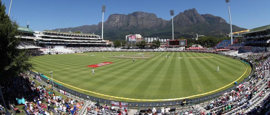 Panoramic view of Newlands Cricket Ground in Cape Town, South Africa, with a cricket match underway and Table Mountain in the background.